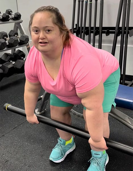 young lady with Down syndrome lifting a fitness bar