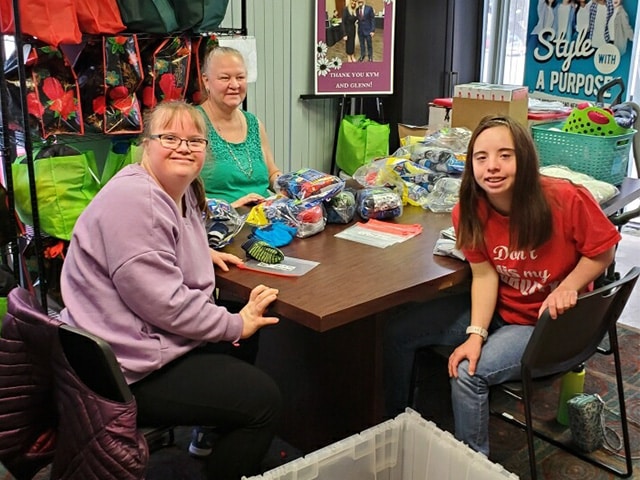 two adults with Down syndrome and one chaperone volunteering.