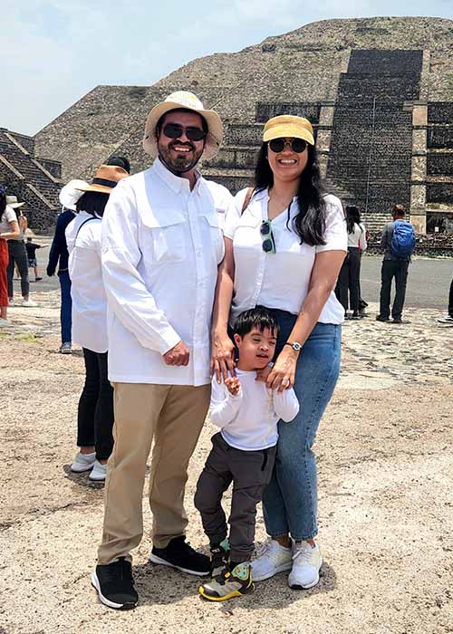 Family with son with Down syndrome standing in front of Aztec ruins