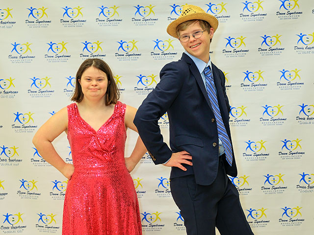 teen boy and girl with Down syndrome posing in front of a backdrop