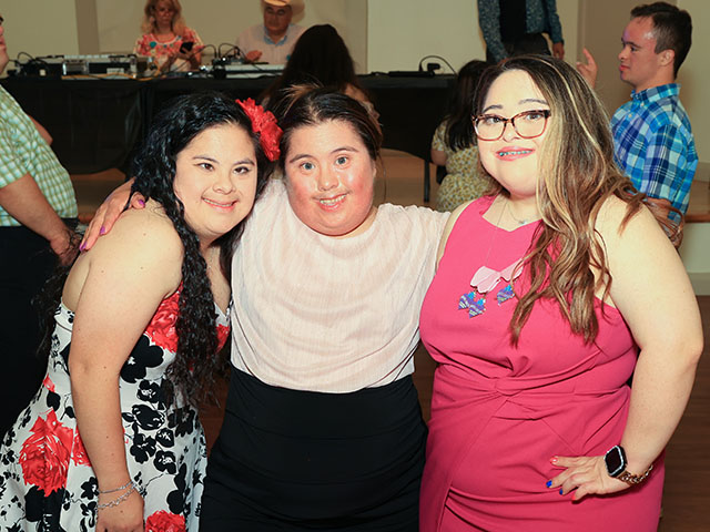 3 adults with Down syndrome smiling at the camera